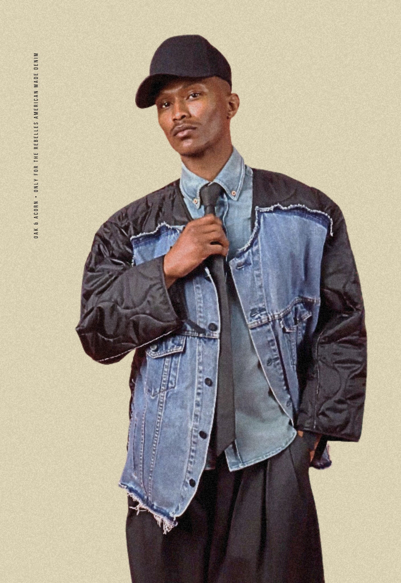 Man wearing a black quilted repurposed denim jacket over a light denim shirt and a black denim tie on a beige background