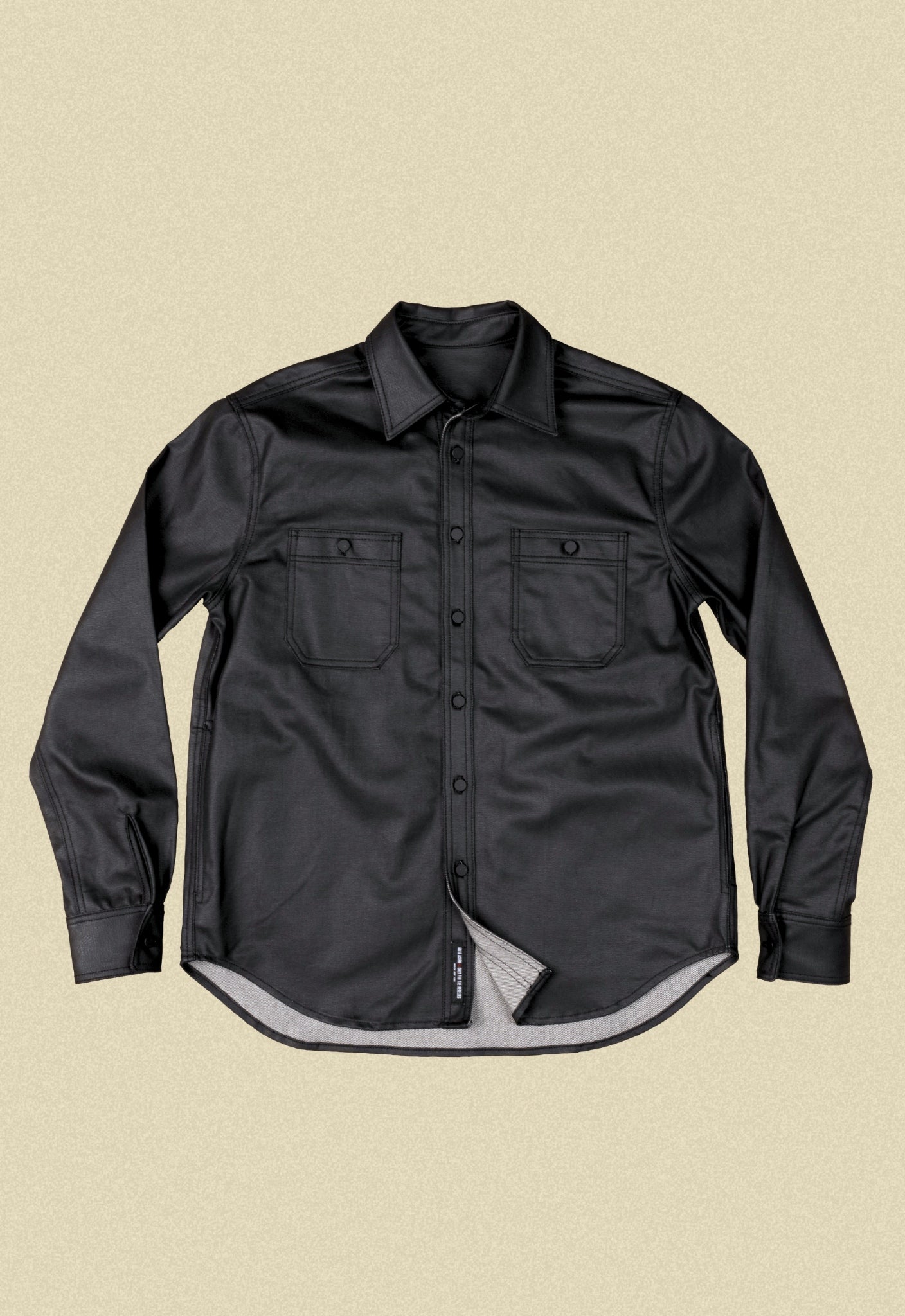 Black denim button-up chore shacket on a beige background