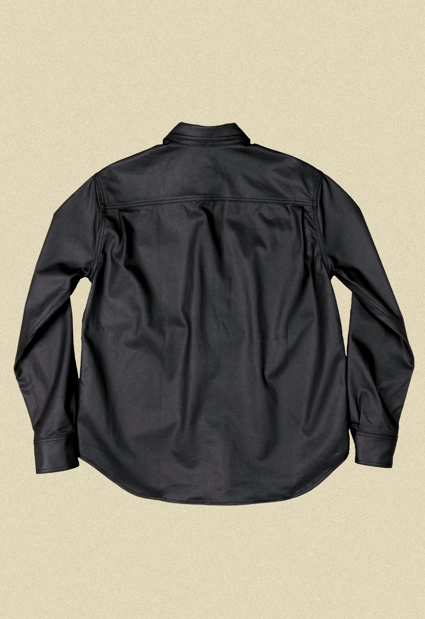 Black denim button-up chore shacket on a beige background