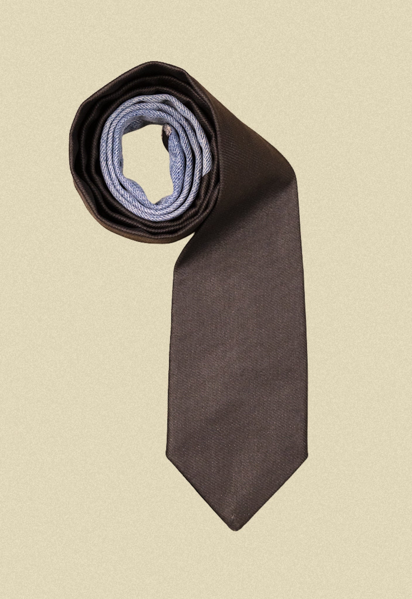 Repurposed coated black and blue denim tie on a beige background