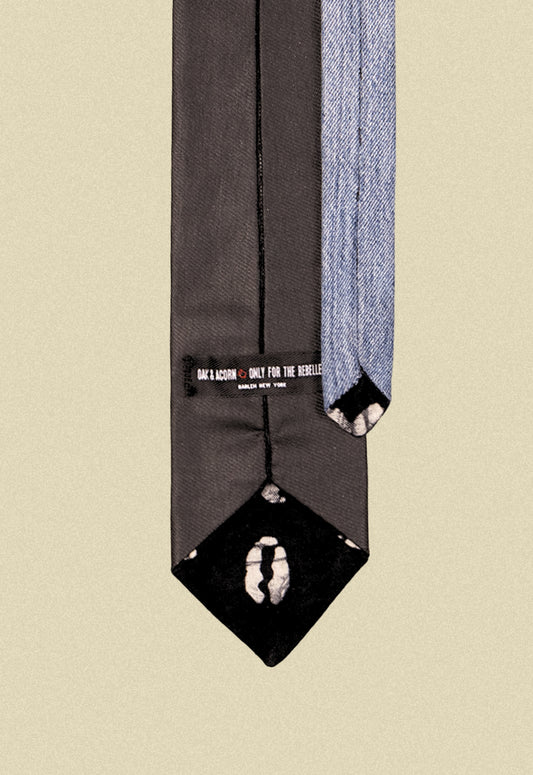 Repurposed coated black and blue denim tie with black sun pattern print fabric detail on a beige background