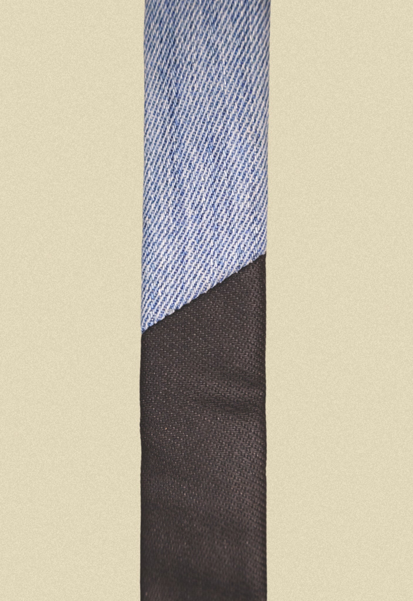 Repurposed coated black and blue denim tie on a beige background