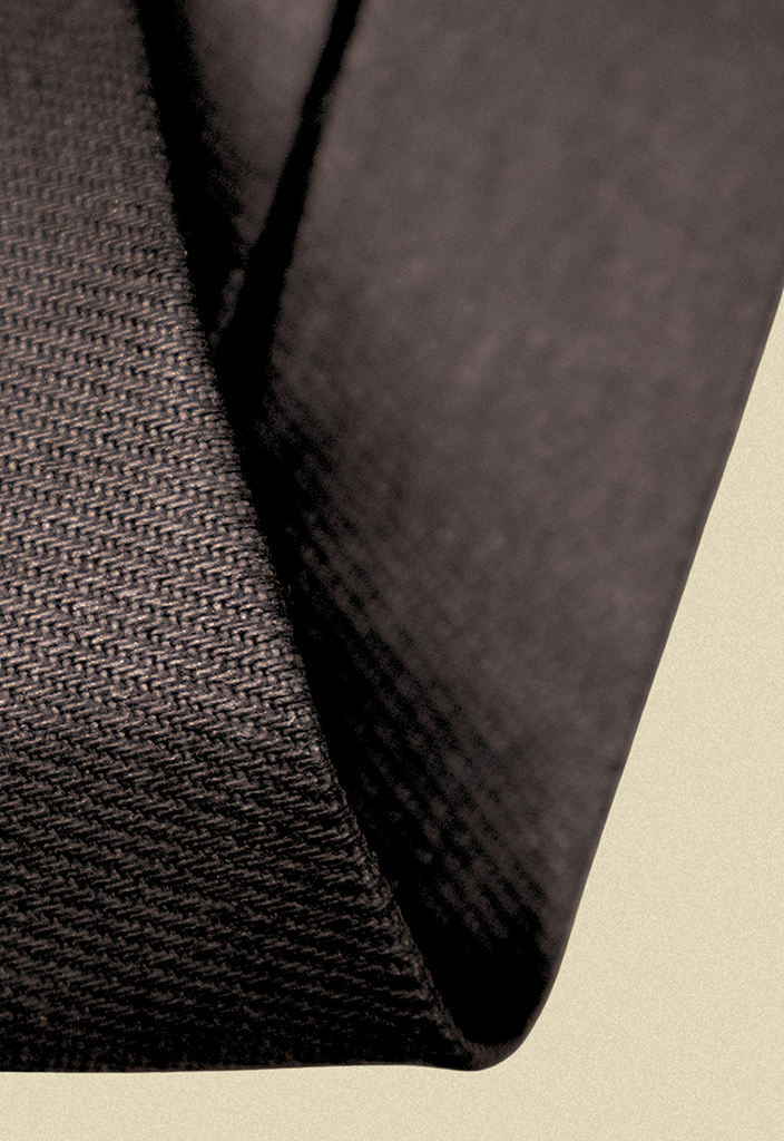 Repurposed coated black and blue denim tie on a beige background